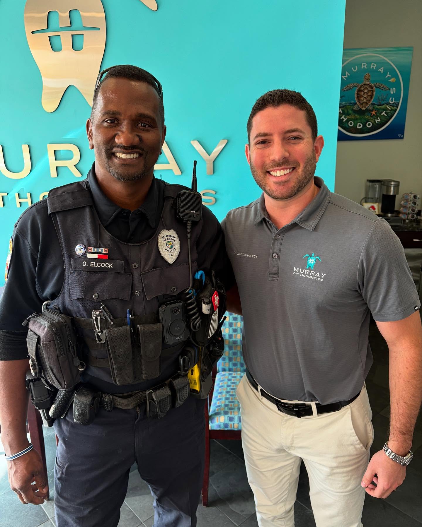 Dr. Jonathan Murray with a Palm Beach Gardens police officer smiling together at Murray Orthodontics office