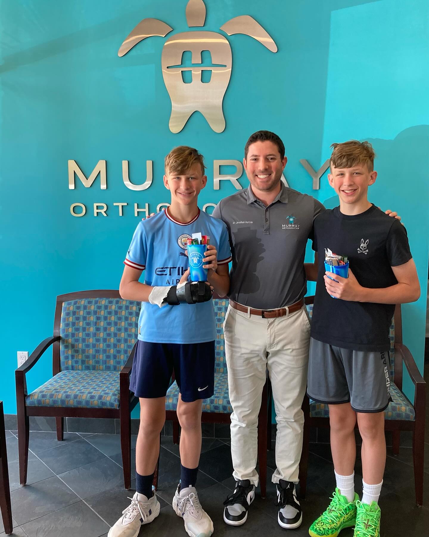 Orthodontist near Wellington, FL — Dr. Jonathan Murray with teen patients holding braces care kits at Murray Orthodontics