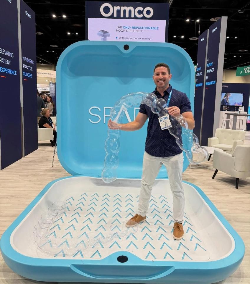 Dr. Jonathan Murray, orthodontist for braces in Royal Palm Beach, FL, holding a giant clear aligner at the AAO Annual Session