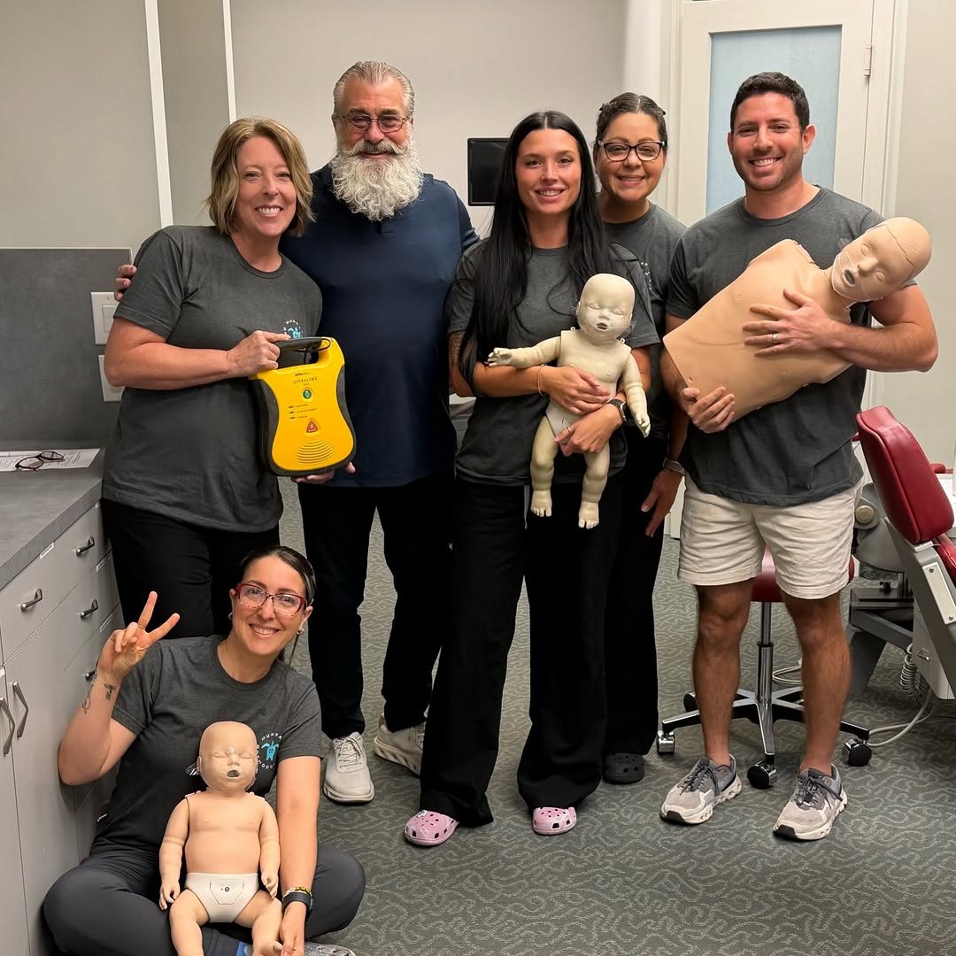 Murray Orthodontics team holding CPR training manikins after renewing their CPR certification at the Palm Beach Gardens office near West Palm Beach